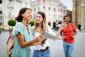Happy traveling tourists friends sightseeing with map in hand